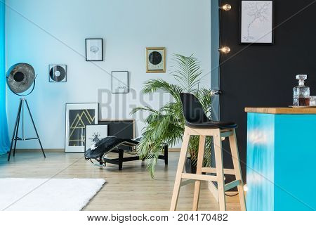 Vinyl records and designer lamp in spacious studio with wooden barstool at kitchen island