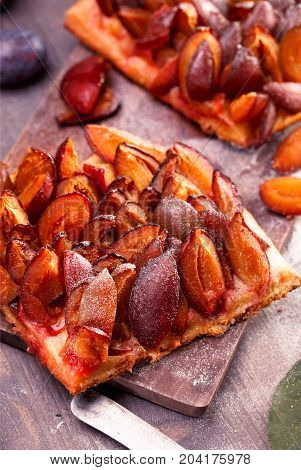 Slicesd german plum cake on wooden table