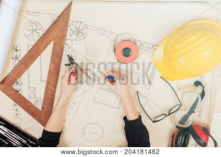 Architect drawing on a blueprint with a compass and ruler.