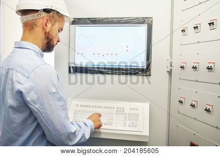 engineer controls technological equipment from remote control board. Scada system for automation equipment.