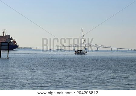 A sailboat with the Frances Scott Key bridge in the background.