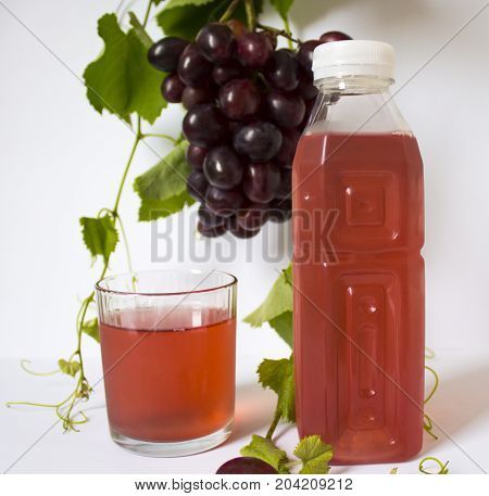 grapes on a white background. a bunch of grapes. grapes, green leaves. dark blue grapes. bottle of juice
