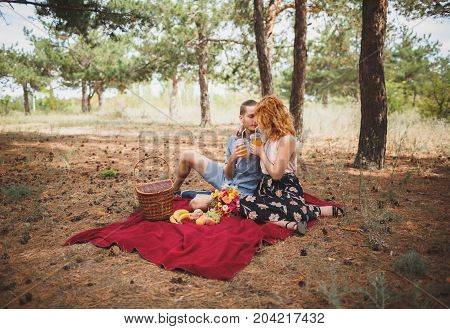 Image of female and manle with bright picnic, sitting in the forest. Lifestyle concept.
