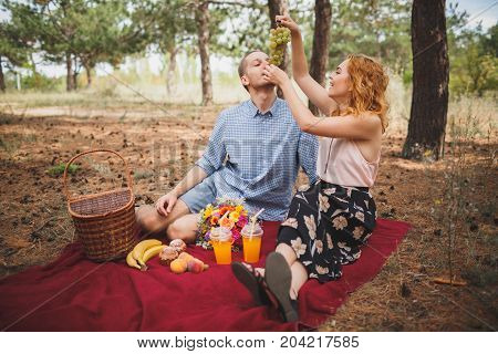 Image of female and manle with bright picnic, sitting in the forest. Lifestyle concept.
