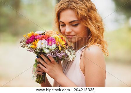 Close-up portrait photo of happy woman with colorful flowers in the forest. Lifestyle and romantic concept.