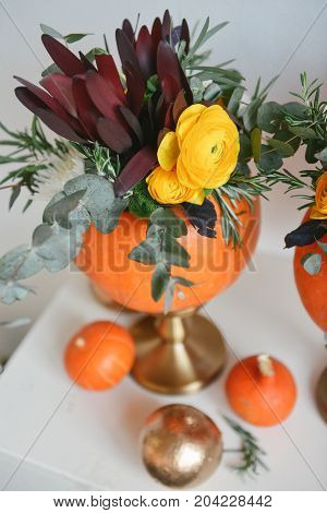 Beautiful autumn floral bouquet in a pumpkin vase. Preparing for Halloween. Table setting for the wedding
