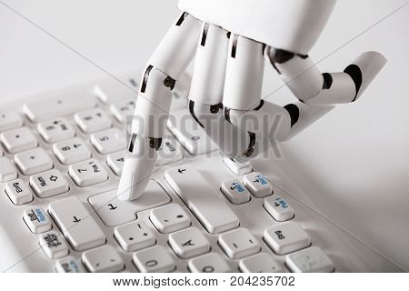 Close-up Of Robotic Hand Pressing Enter Key On Keyboard