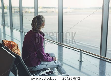Girl at the airport window looking outside