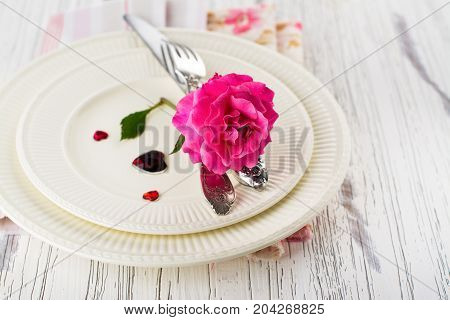 Valentines day table setting with white plates, hearts and rose. Space for text. Holidays background