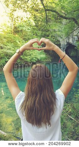 Young woman holding heart-shape for the beautiful nature.