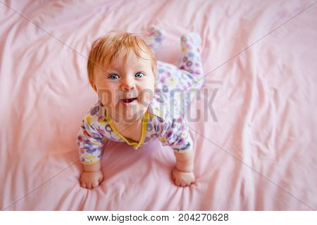 cute little baby learning to crawl, curious smiling child exlores the world around, early child development