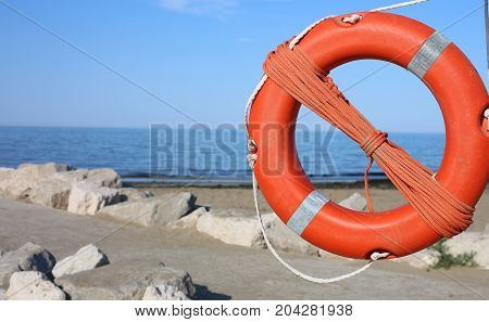 Orange Lifebuoy For People Near Rocks At The Sea In Summer