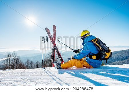 Rearview Shot Of A Skier Sitting On The Snow On Top Of The Mountain Taking Selfies With His Action C