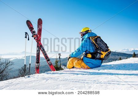 Rearview Shot Of A Skier Sitting On Top Of The Mountain Near His Skiing Equipment Relaxing Enjoying