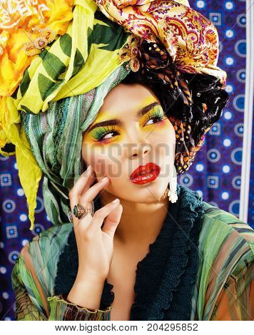 beauty bright woman with creative bright make up, many shawls on head like cubian, ethno look closeup
