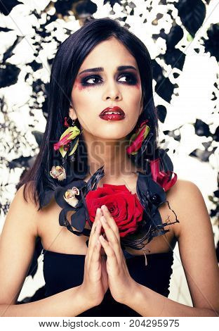 pretty brunette woman with rose jewelry, black and red, bright make up kike a vampire closeup red lips, halloween concept