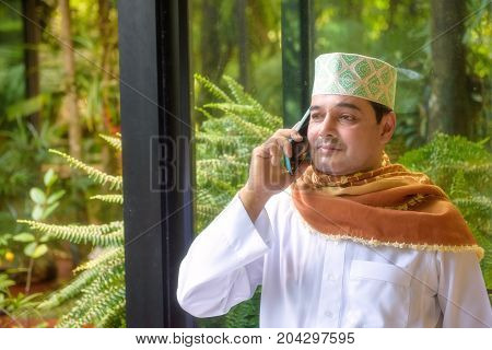Portrait of Arab muslim man with hat and hijab onuse smart phone and look forward .