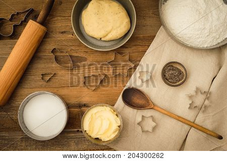 Flatlay collection of tools and ingredients for baking vegan Christmas cookies with margarine and chia seeds as egg replacement on a dark wooden table. Shot from above