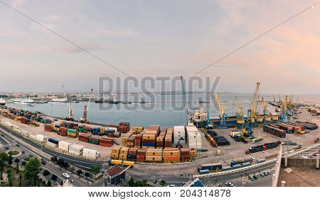 ALBANIA DURRES - September 22 2015: Panorama of the cargo terminal of the international port of Durres at sunset. Unloading of the tanker by cargo cranes. A platform for storing sea freight containers. Cruise liners and cargo ships are moored in the port