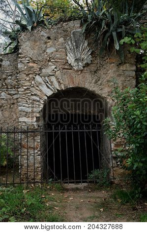 Abandoned wine cellar arched gate with antique acroterion decorative ornament.