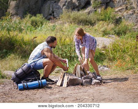 Couple in the forest. Hands of a man and girl who in the forest among the dry, withered leaves kindle fire.