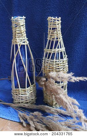 two glass fragile blue bottle weaved willow stay on blue background for new wine