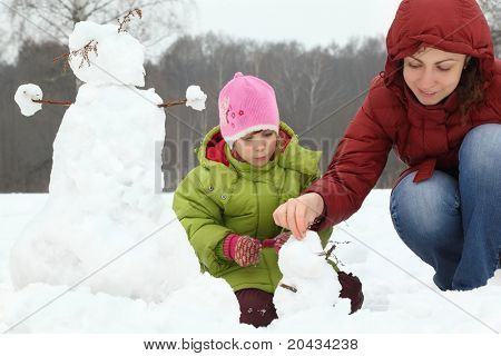 어머니와 여자 겨울 야외 sculp에 작은 눈사람
