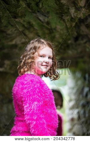 View of Young little girl portrait looking and smiling at the camera while exploring in an old castle