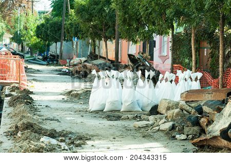Sand in white plastic nylon bags on the street reconstruction site