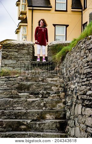 View of Young little girl portrait looking and smiling standing at top of rocky stairs