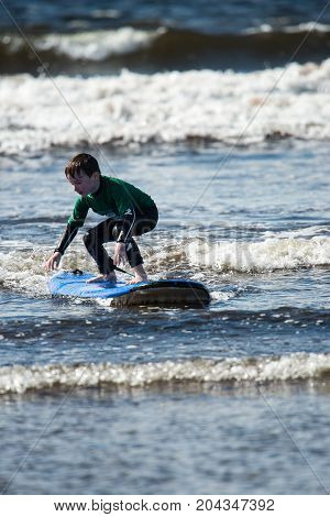 View of Young little boy on beach taking surfing lessons