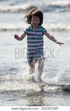 View of Young little girl on beach playing in the surf
