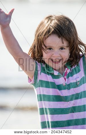 View of Young little girl on beach playing in the surf