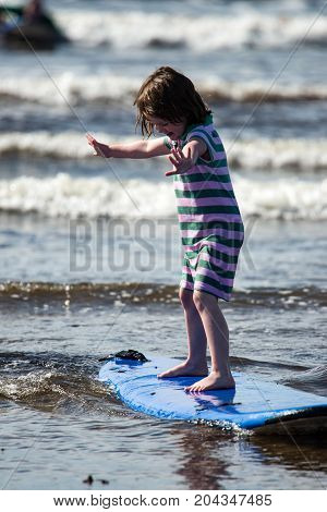 View of Young little girl on beach taking surfing lessons