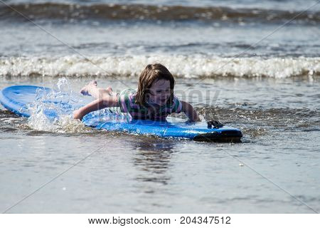 View of Young little girl on beach taking surfing lessons