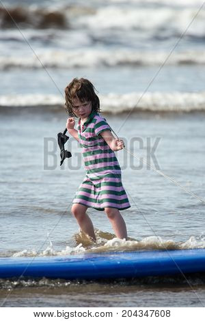 View of Young little girl on beach taking surfing lessons