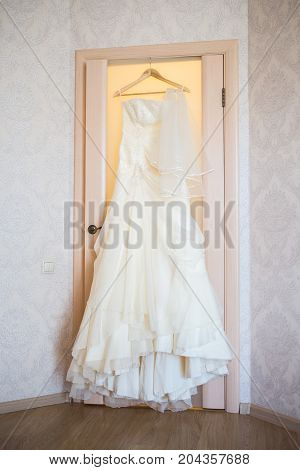 Elegant flowing wedding dress hanging on door