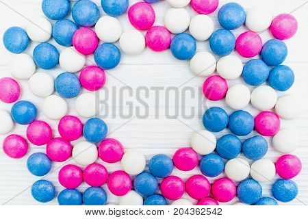 Frame from colorful mint coated candies texture on white wooden background. Top view. Copy space