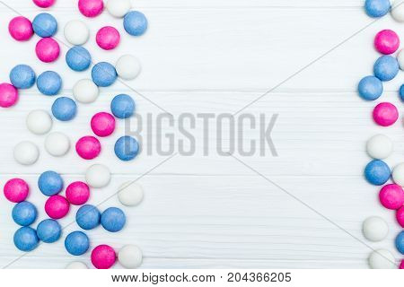 Frame from colorful mint coated candies texture on white wooden background. Top view. Copy space