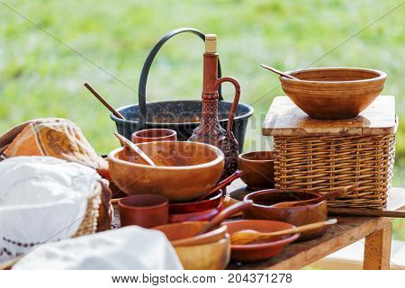 Wooden table with old fashioned wooden and earthenware crockery. Historical reconstruction of 19 century.