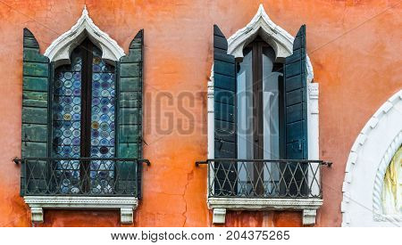 Ogival mosaic Venetian windows with shutter. Houses peeling off from dampness in Venice