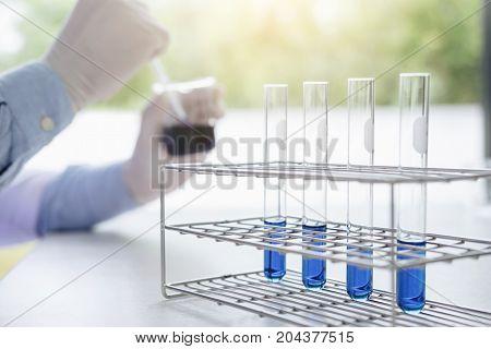Scientist or medical in lab coat working in biotechnological laboratory equipment holding test tube for research with mixing reagents in glass flask in laboratory.