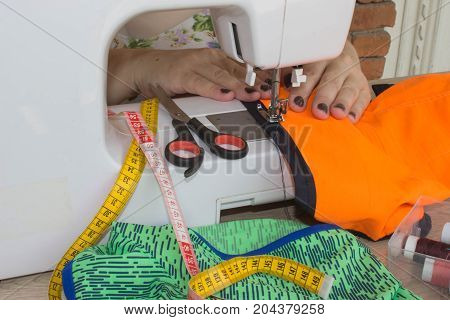 processes of sewing on the sewing machine sew women's hands sewing machine. Female tailor threading leather material on sewing machine. designer making a garment in her workplace