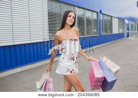 Female shopping. Lady carries paper bags with text hot sale, big sale. Smiling woman character with gift boxes in the mall. For sales and discounts. shopping, fashion, style and people concept.