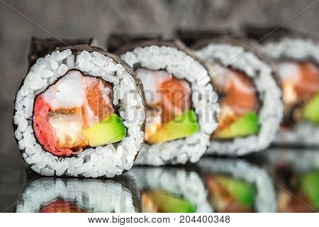 Sushi roll with salmon, shrimps and avocado over cocnrete background