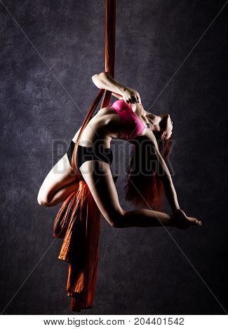 Beautiful sexy dancer on aerial silk, graceful contortion, acrobat performs a trick on a ribbons.