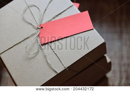 A stack of craft boxes with gifts tied with a cord with a red tag