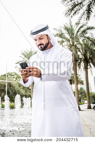 Arabic businessman with traditional dress in Dubai with smartphone