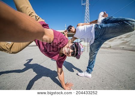 Two bbys doing some stunts - Street artist breakdancer taking an acrobatic selfie outdoors