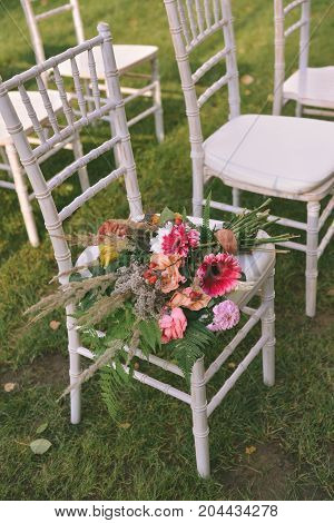 autumn wedding bouquet lies on a white chair